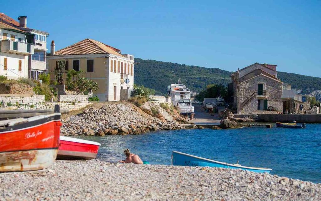 eine Person, die am Strand neben dem Wasser sitzt in der Unterkunft Seaview apartment Bambo in Komiža