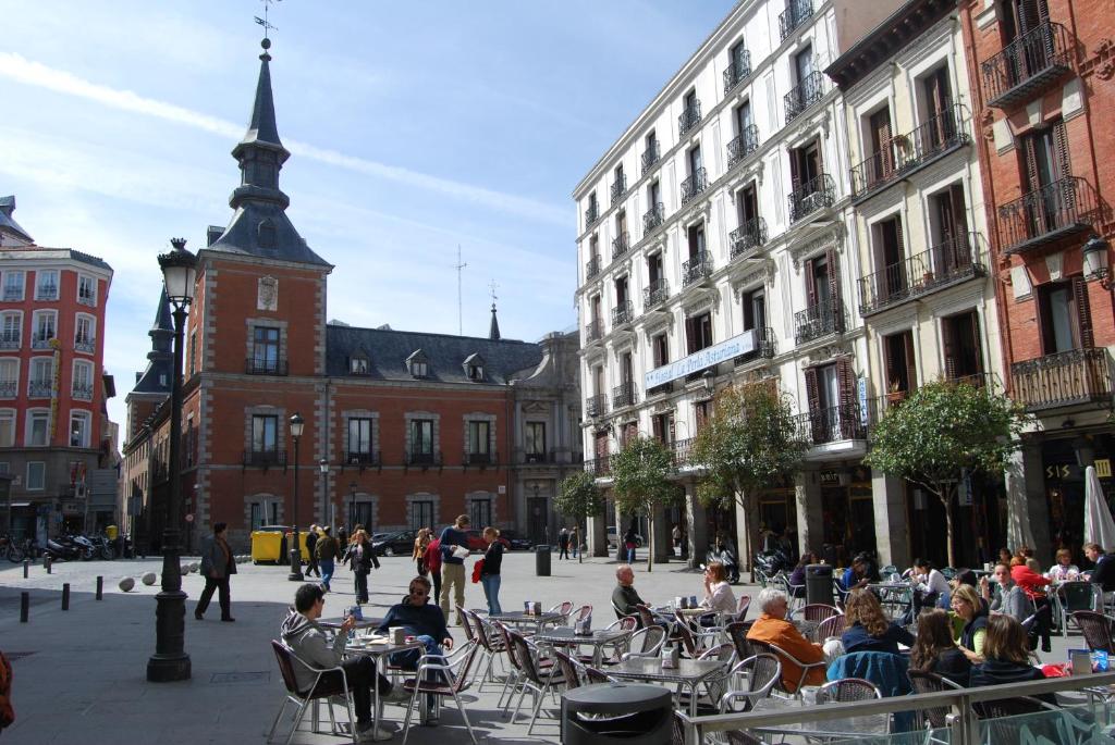 un gruppo di persone seduti ai tavoli in una strada di città di Hostal La Perla Asturiana a Madrid