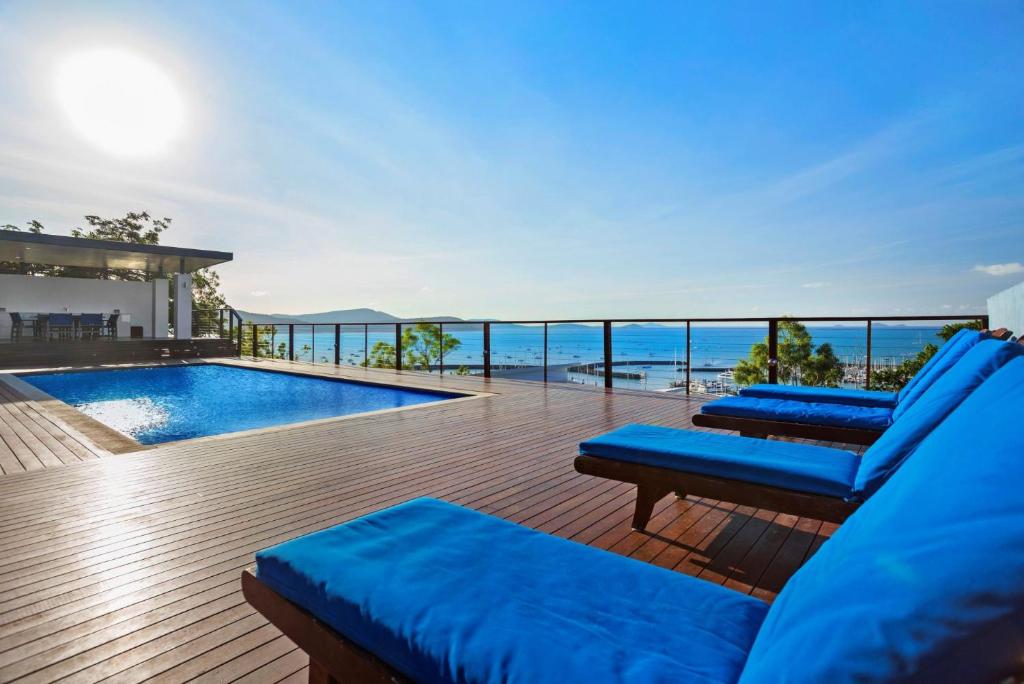 a balcony with blue pillows and a swimming pool at Nautilus On The Hill - Airlie Beach in Airlie Beach