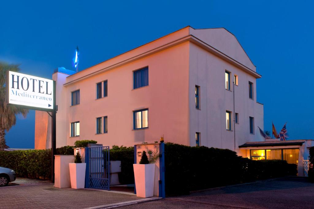 a hotel with a sign in front of a building at Hotel Mediterraneo in Lido di Latina 