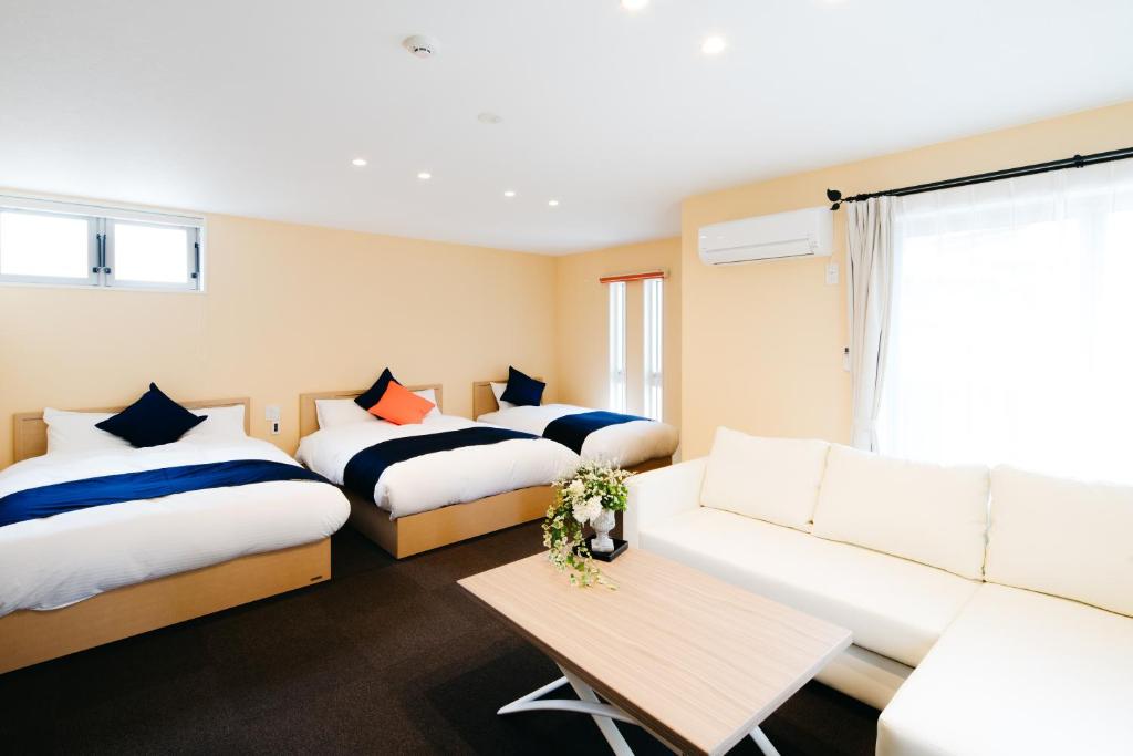 une chambre d'hôtel avec deux lits et un canapé dans l'établissement FUKUOKA MOJIKO STAY, à Kitakyūshū