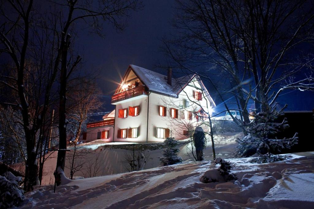 a large white house in the snow at night at Pensjonat Rudy in Stronie Śląskie