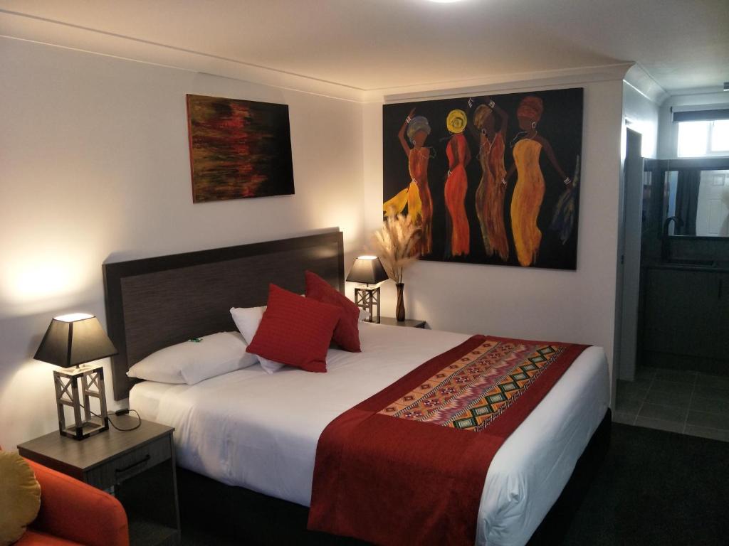 1 dormitorio con 1 cama y una pintura en la pared en Alabaster Motor Inn en Taree