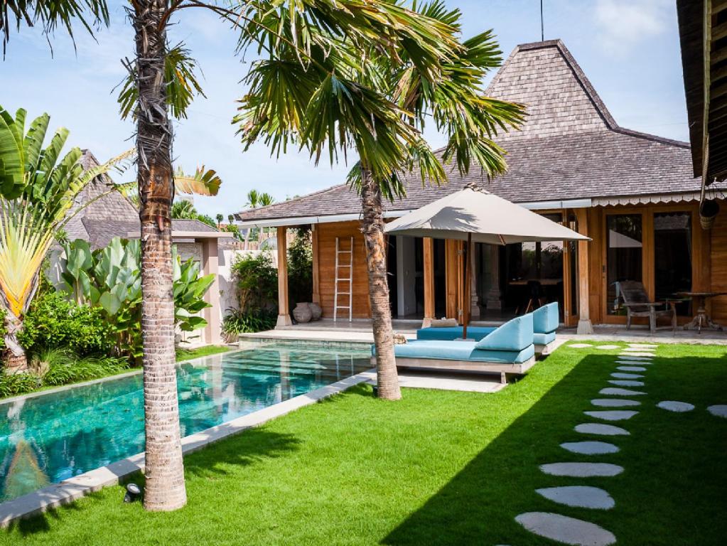 a backyard with a swimming pool and palm trees at Villa Du Ho in Kerobokan