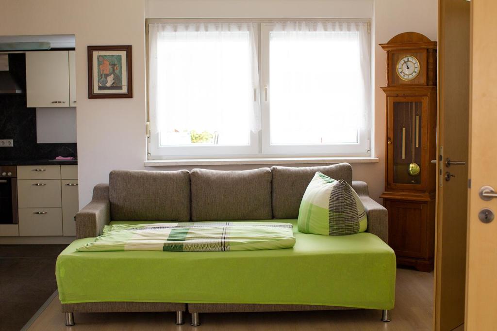 a green couch in a living room with a clock at Pia Fewo Günzburg in Günzburg