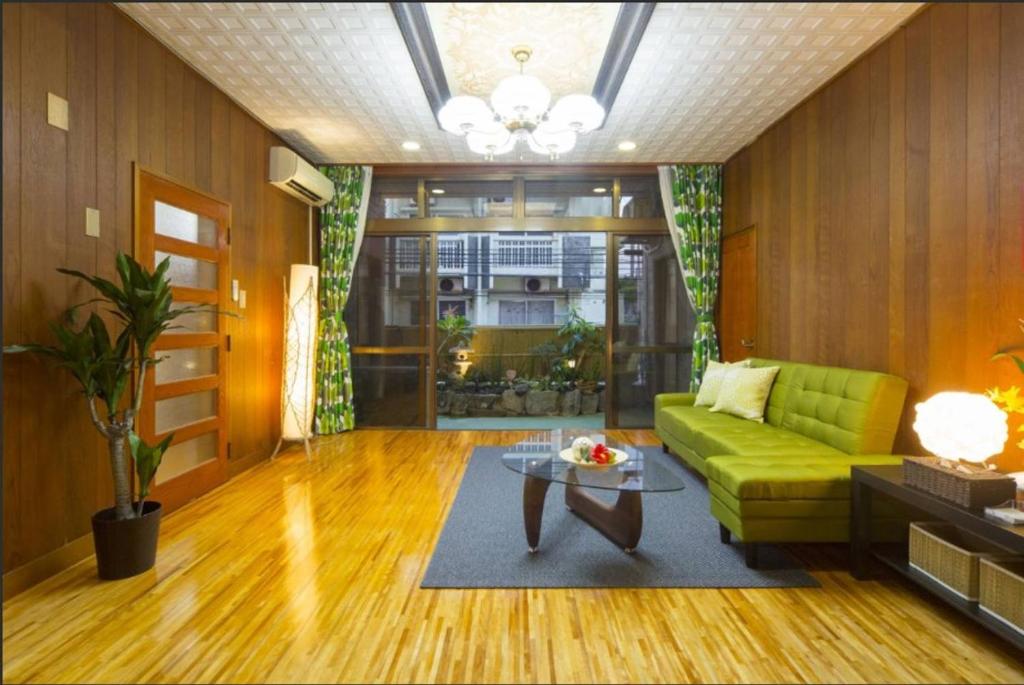 那覇市にあるGuest House Matsuyamaの緑のソファとテーブルのあるリビングルーム