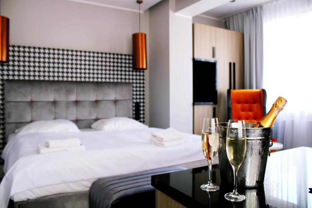 une chambre d'hôtel avec un lit et deux verres de champagne dans l'établissement Hotel Pomarańczowa Plaża ex Bursztyn, à Sopot