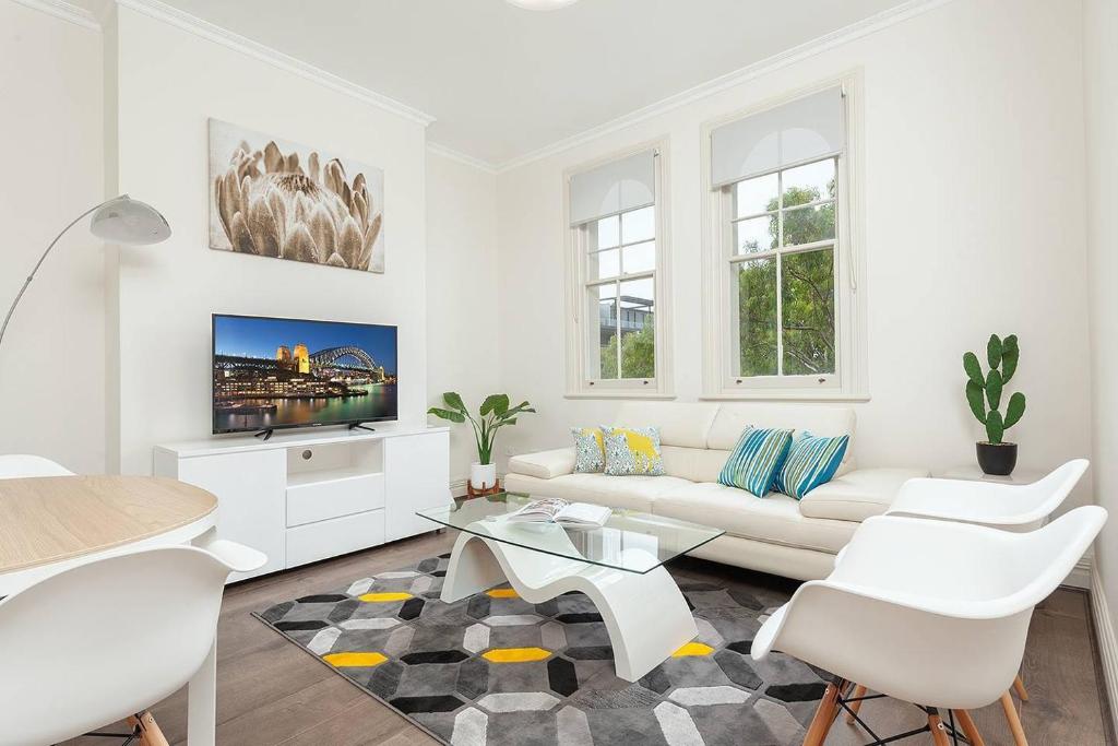 a white living room with a white couch and a table at STUNNING SYDNEY HOME 1 in Sydney