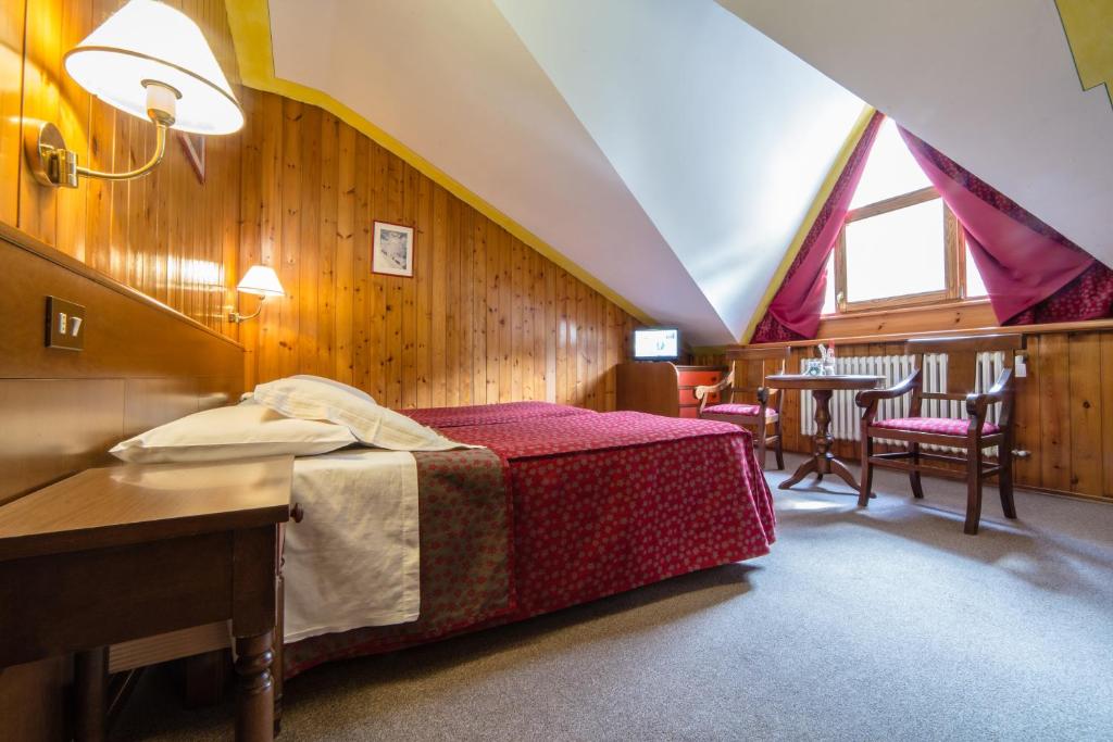a bedroom with a bed and a table and chairs at Hotel Beau Sejour Pré-Saint-Didier in Pré-Saint-Didier