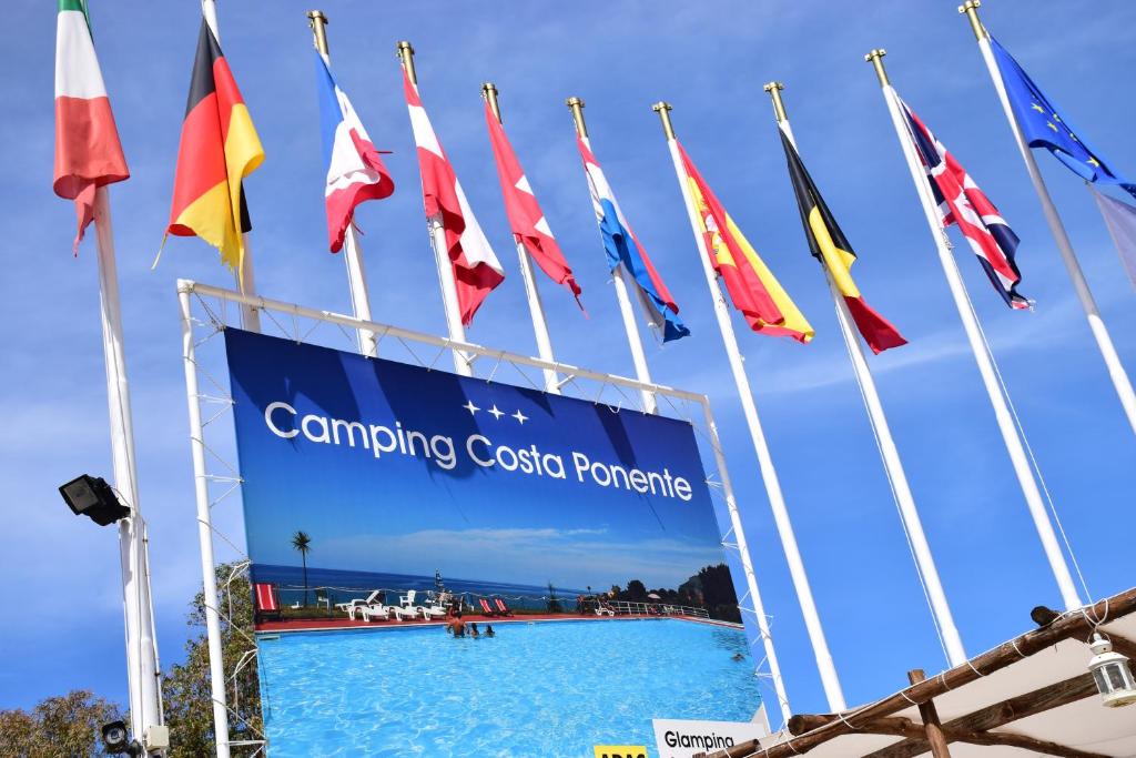 a group of flags in front of a swimming pool at Camping Costa Ponente in Cefalù
