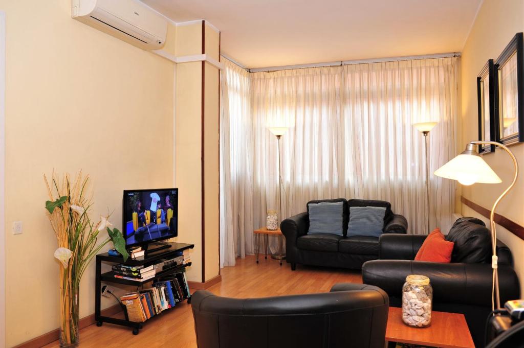 ein Wohnzimmer mit einem Sofa und einem TV in der Unterkunft Hostal Bejar in Barcelona