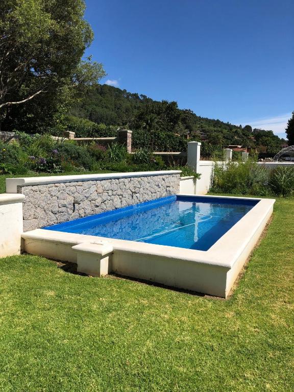 a swimming pool in a yard with a stone wall at d'Olyfboom Guest House B & B in Paarl