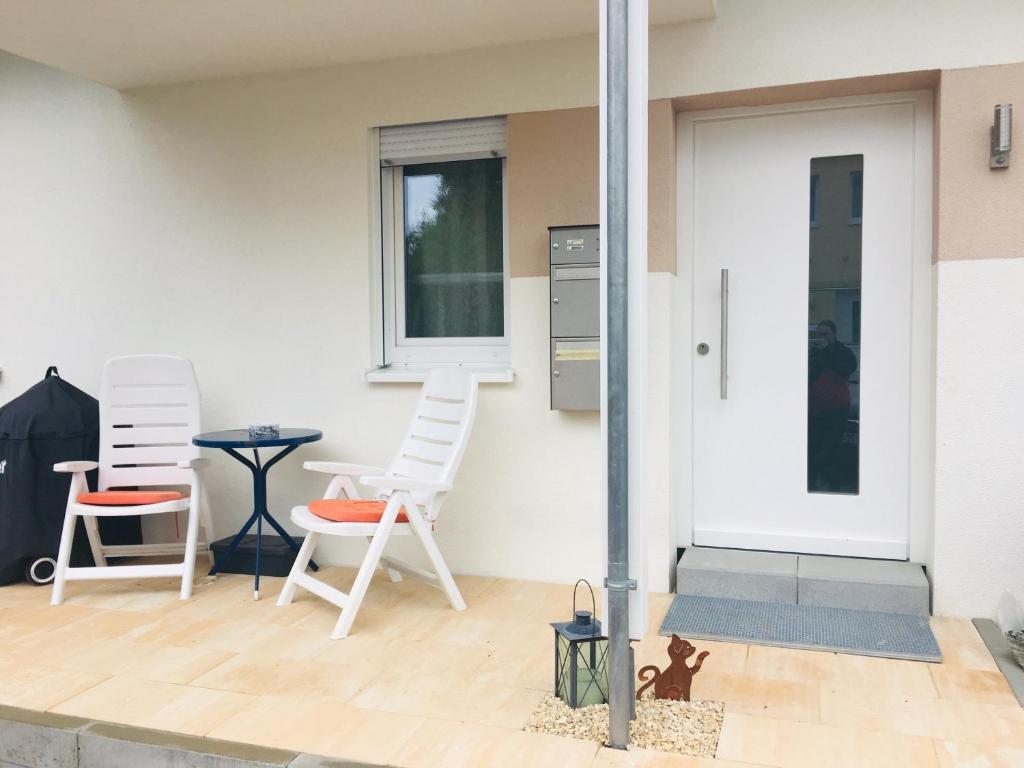 a patio with white chairs and a table and a door at Ferienwohnung im Spessart / Aschaffenburg in Johannesberg