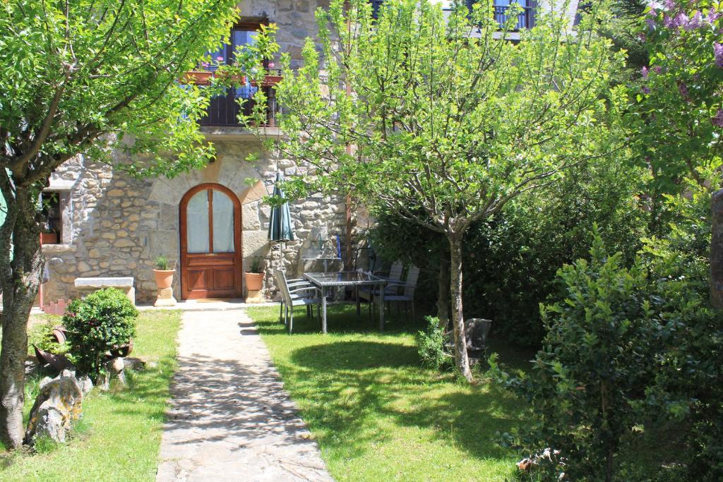 a garden with a wooden door and a table and trees at Casa MENDILUCE in El Pueyo de Jaca