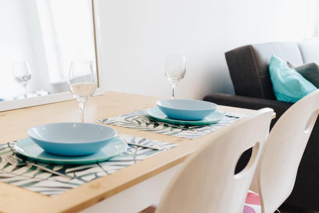 stół jadalny z dwoma talerzami i kieliszkami do wina w obiekcie Apartament Gdynia Centrum w mieście Gdynia