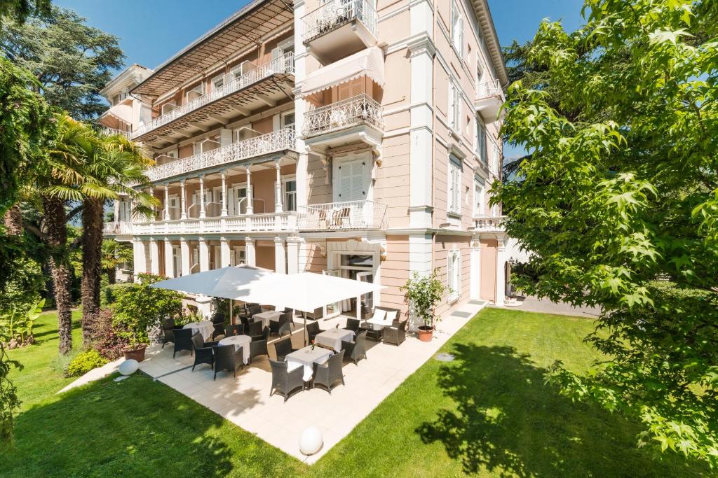 an exterior view of a building with tables and chairs at Hotel Adria in Merano