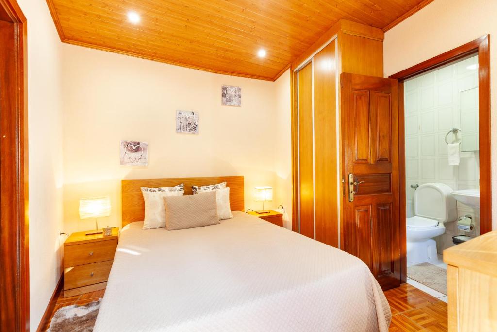 a bedroom with a white bed and a bathroom at Casa das Bonecas in Vieira do Minho
