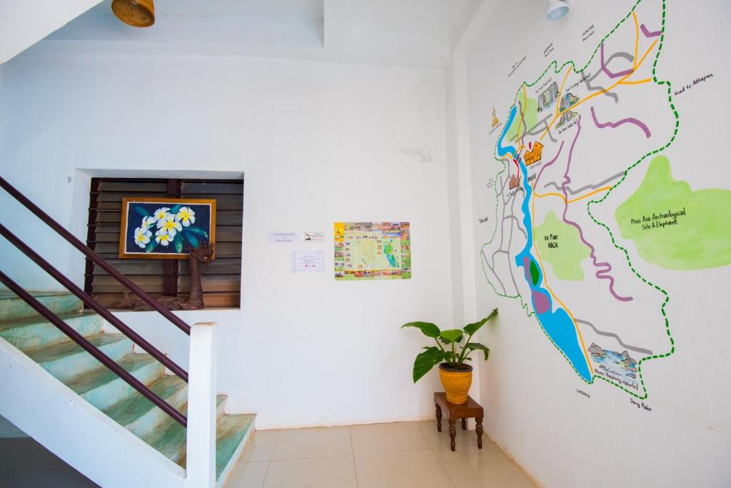 a living room with a staircase and a map on the wall at 1918’s HOSTEL in Pakse