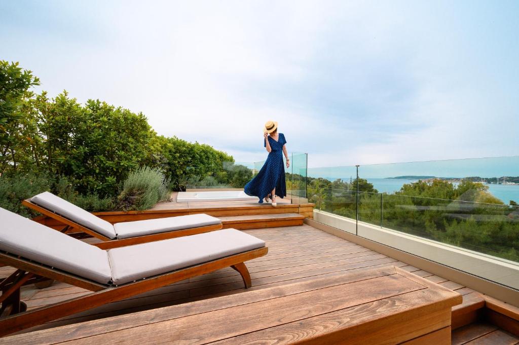 a woman in a blue dress walking on a deck at Somewhere Vouliagmeni in Athens