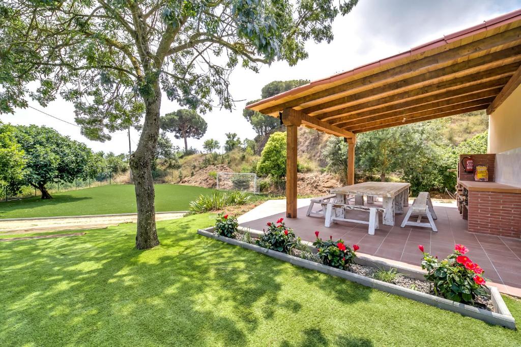 un patio trasero con mesa de picnic y pérgola de madera en Vivalidays Can Palomo, en Palafolls