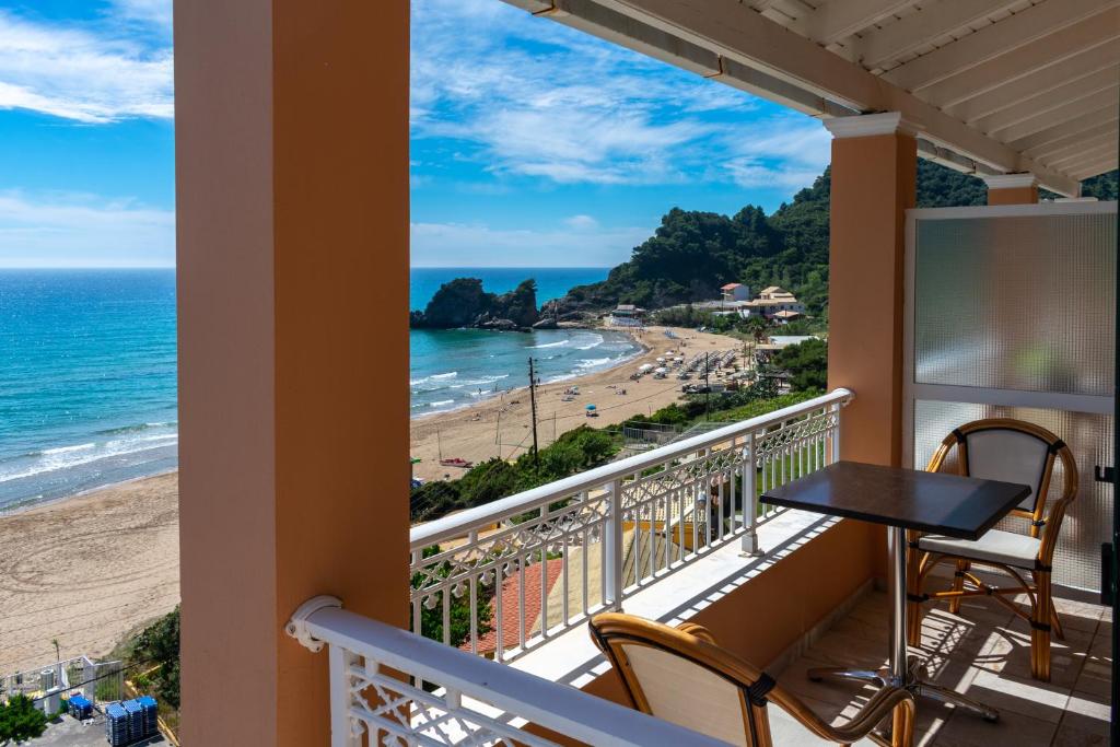 een balkon met een tafel en stoelen en uitzicht op het strand bij Naftis Apartments in Pelekas