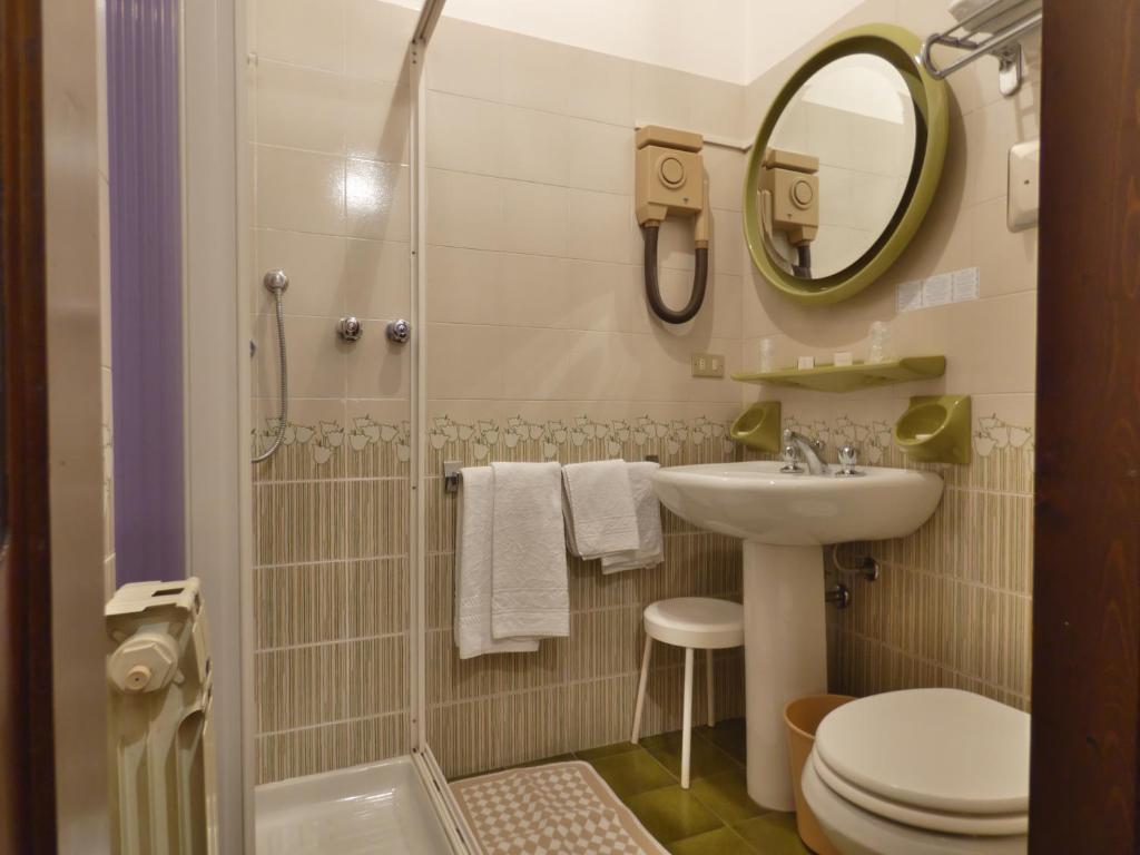 łazienka z umywalką, toaletą i lustrem w obiekcie Hotel Derby w Sirmione