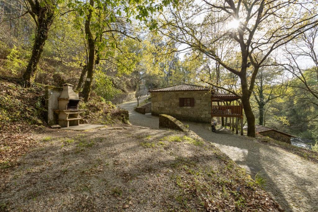 un chemin de terre avec un bâtiment et des arbres dans l'établissement Quinta do Rio Homem, à Caldelas