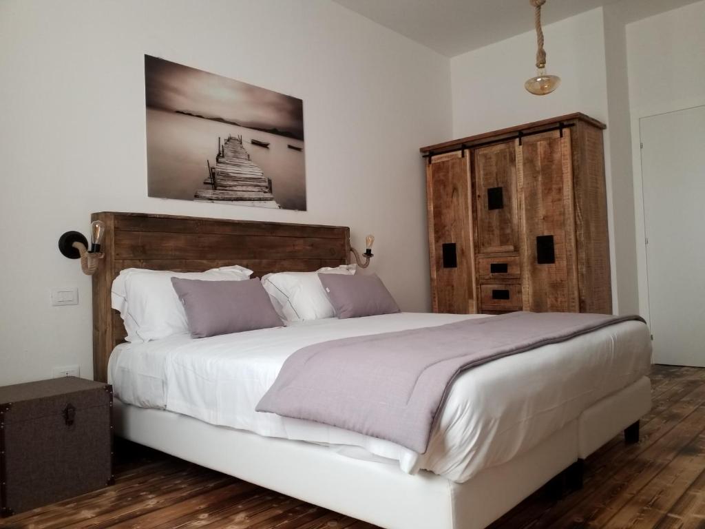 a bedroom with a large white bed with a wooden headboard at Piccolo Feudo in Sanluri