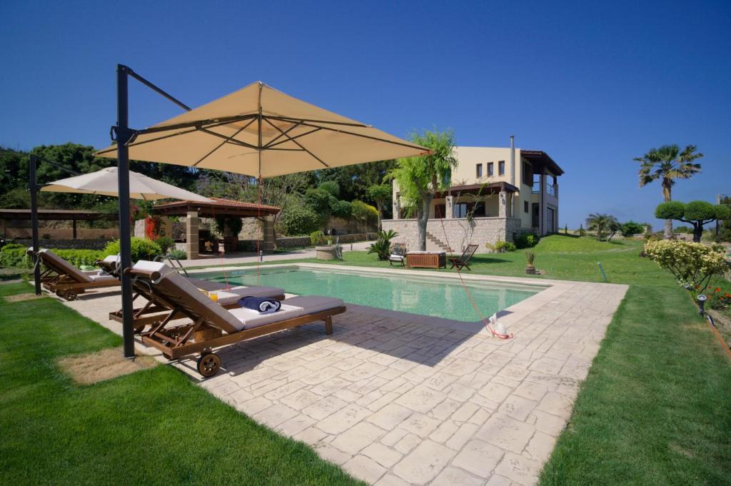 a pool with an umbrella and benches next to a house at Villa Russelia in Kalavárda