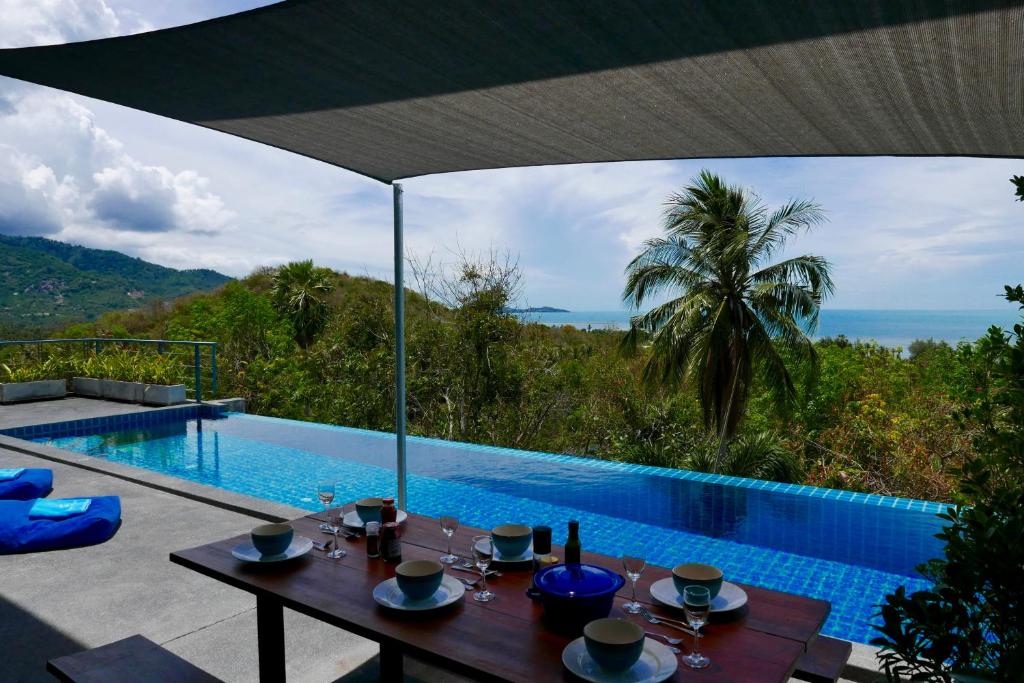 a dining table with a view of a swimming pool at Sky Villas Philippa with Free Car in Laem Set Beach