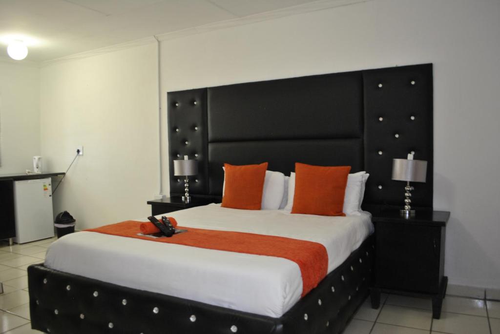a bedroom with a large bed with orange pillows at Lapologa Bed & Breakfast in Tzaneen