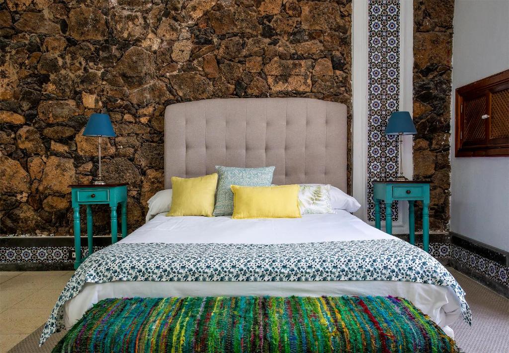 1 dormitorio con 1 cama grande y 2 mesas azules en El Charco Suites en Arrecife