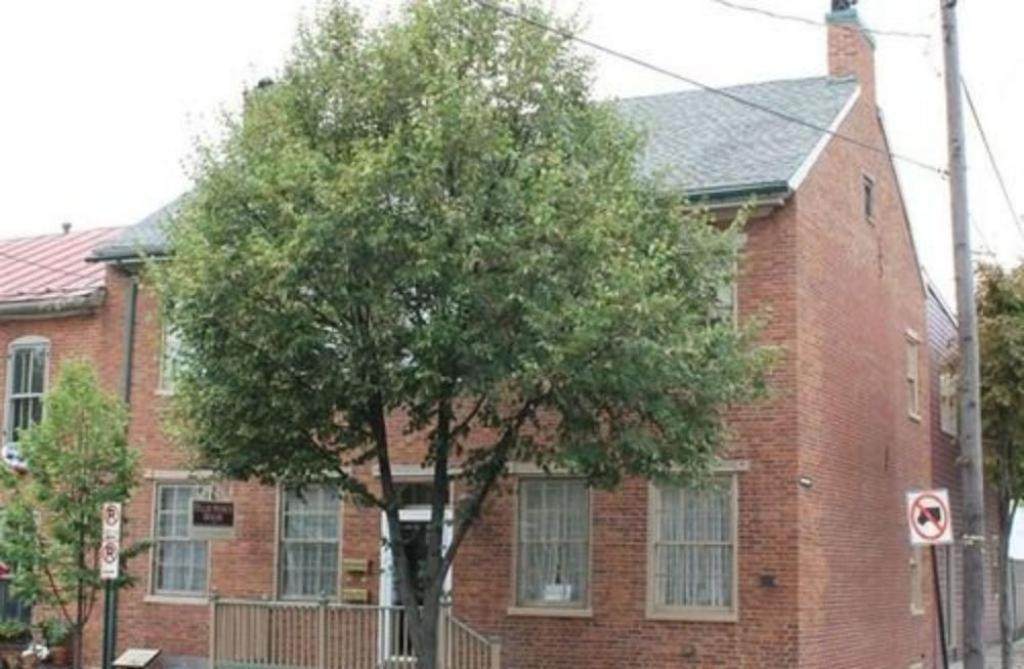 a tree in front of a red brick house at The Tillie Pierce House Inn in Gettysburg