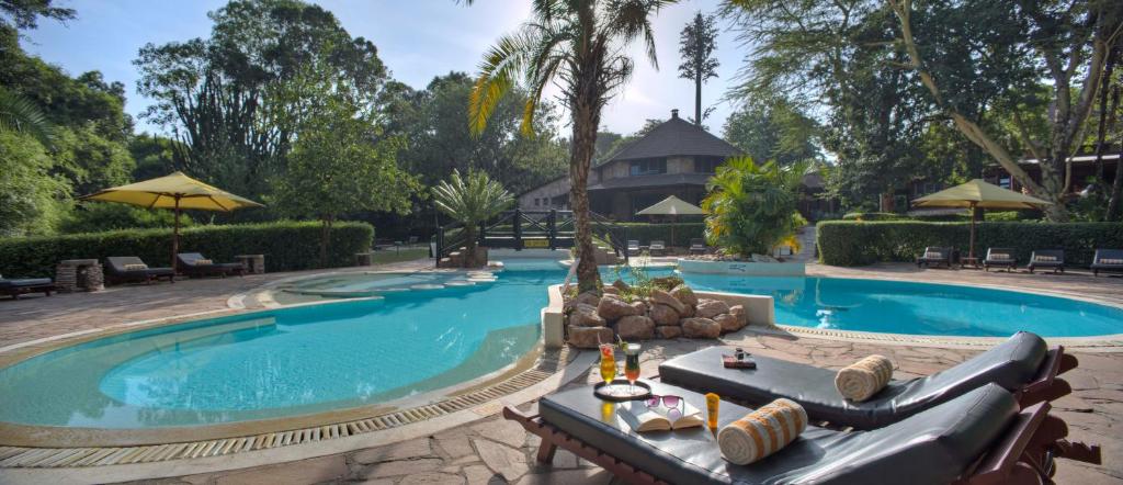 a pool at a resort with chairs and a table at Sarova Mara Game Camp in Sekenani