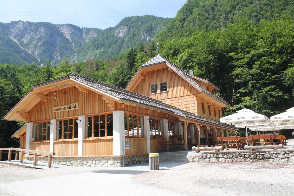 a large wooden building with mountains in the background at Planinski dom Savica in Bohinj