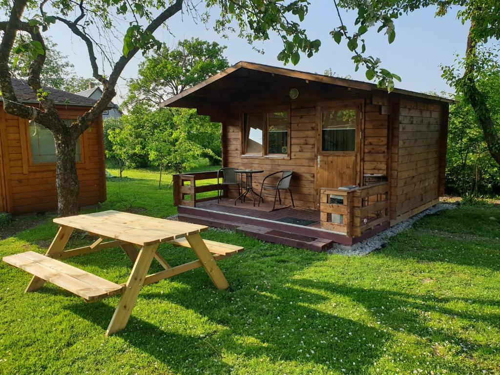 a wooden cabin with a table and a picnic table in the grass at Cozy Summer House with Free Parking near City Center & Beach in Kuressaare
