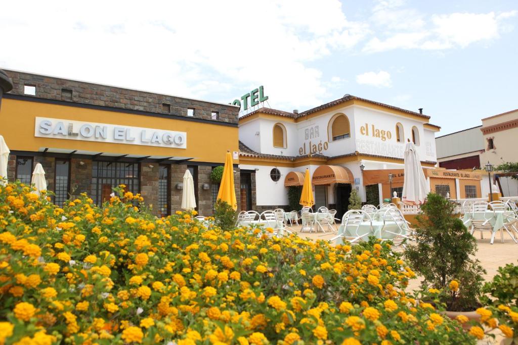 un edificio con mesas, sillas y flores amarillas en Hotel Restaurante El Lago, en Arcos de la Frontera