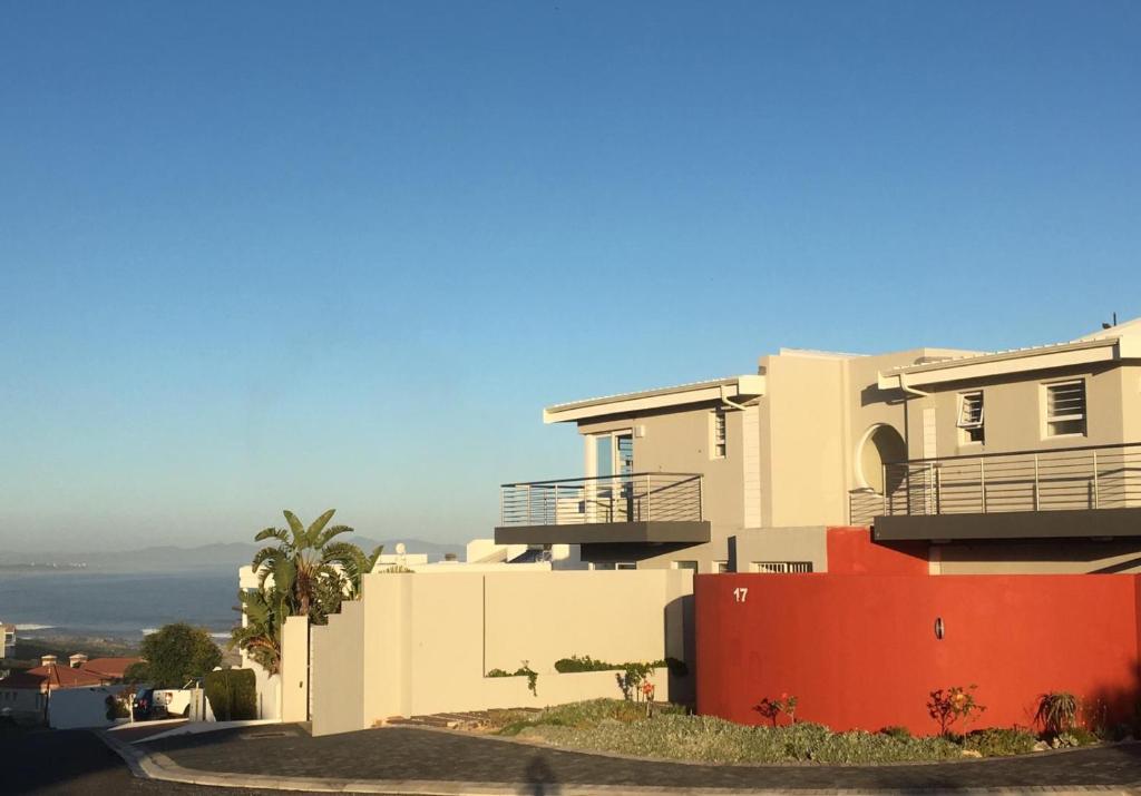 una casa blanca con una valla roja delante de ella en Vermont Hermanus - views, sunny, right on the sea, en Hermanus