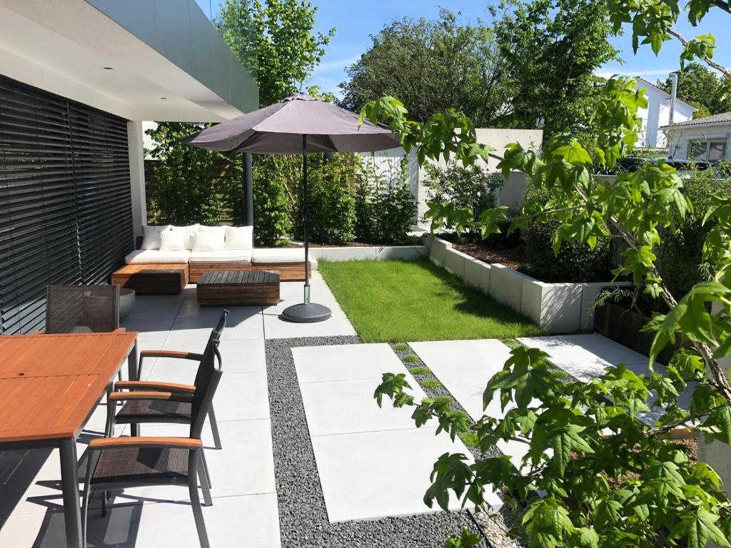 a patio with a table and chairs and an umbrella at seenahe Design-Ferienwohnung Loft Aquamarin in Überlingen
