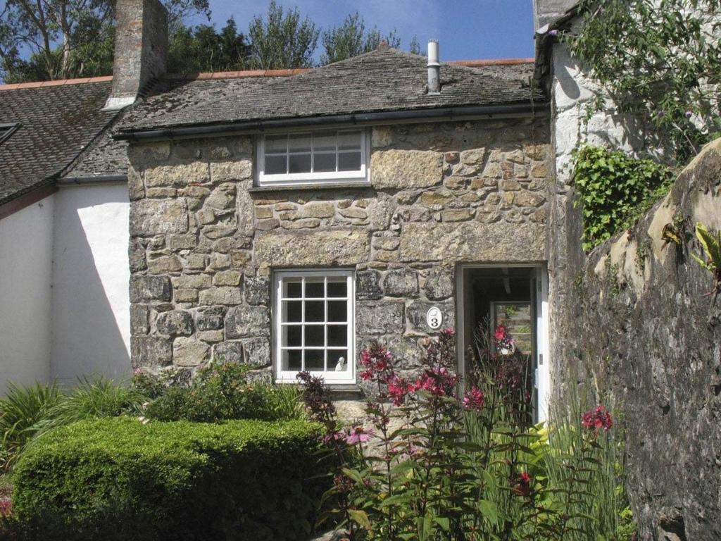 an old stone house with flowers in front of it at White Duck Cottage in Hayle
