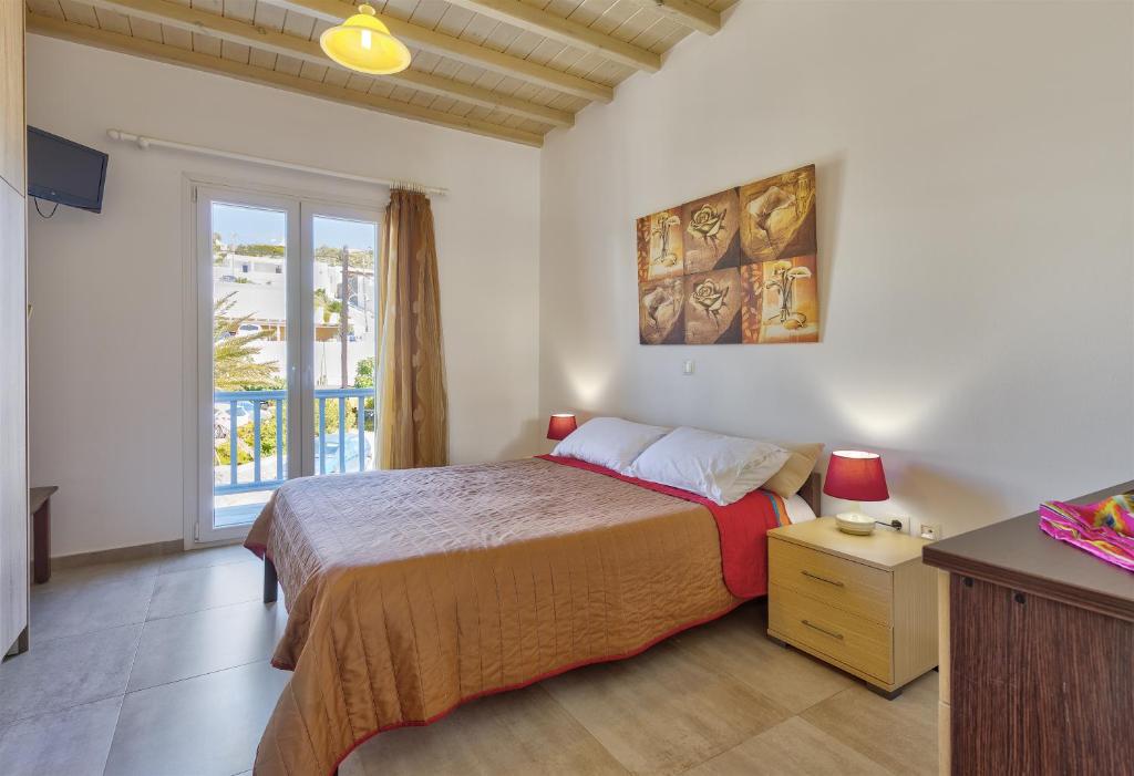 a bedroom with a large bed and a window at Jewel Apartments Mykonos in Ornos