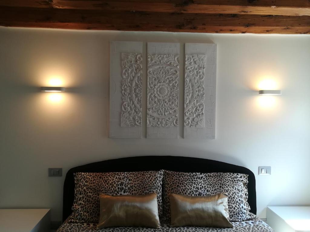 two lights on a wall above a bed with two pillows at Cà Mercante di Spezie in Venice