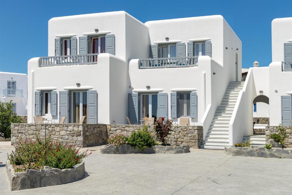a white house with a white wall and a blue door at Jewel Apartments Mykonos in Ornos