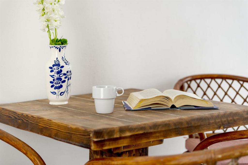 a wooden table with a book and a vase on it at Jewel Apartments Mykonos in Ornos
