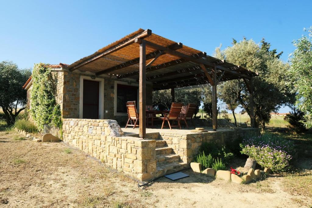 una casa con una pared de piedra y una pérgola de madera en Limnos Stone House en Kalliópi