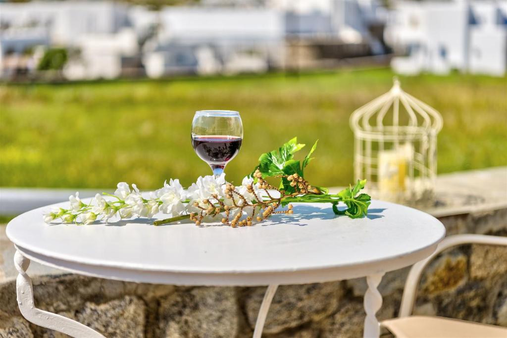 a white table with a glass of wine on it at Jewel Apartments Mykonos in Ornos