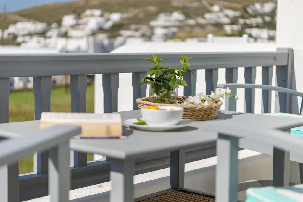 a table with a book and a plant on a balcony at Jewel Apartments Mykonos in Ornos