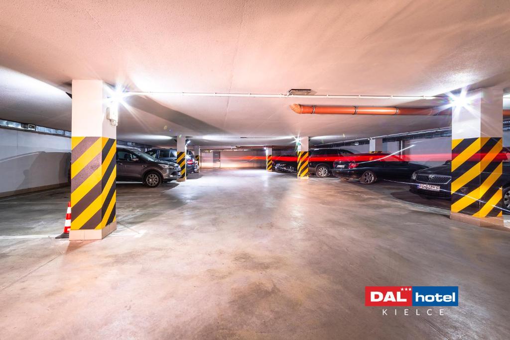 Underground hotel parking with striped safety pillars, parked cars, wide concrete floor, bright overhead lighting.