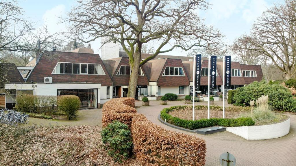 een huis met een boom ervoor bij Fletcher Hotel-Restaurant Wolfheze in Wolfheze