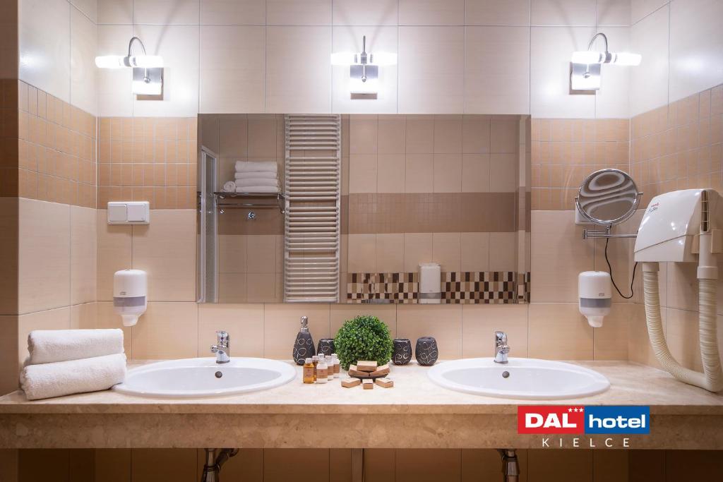 Double vanity with two sinks, mirror, neatly folded towels, toiletries, mounted hairdryer, warm lighting.